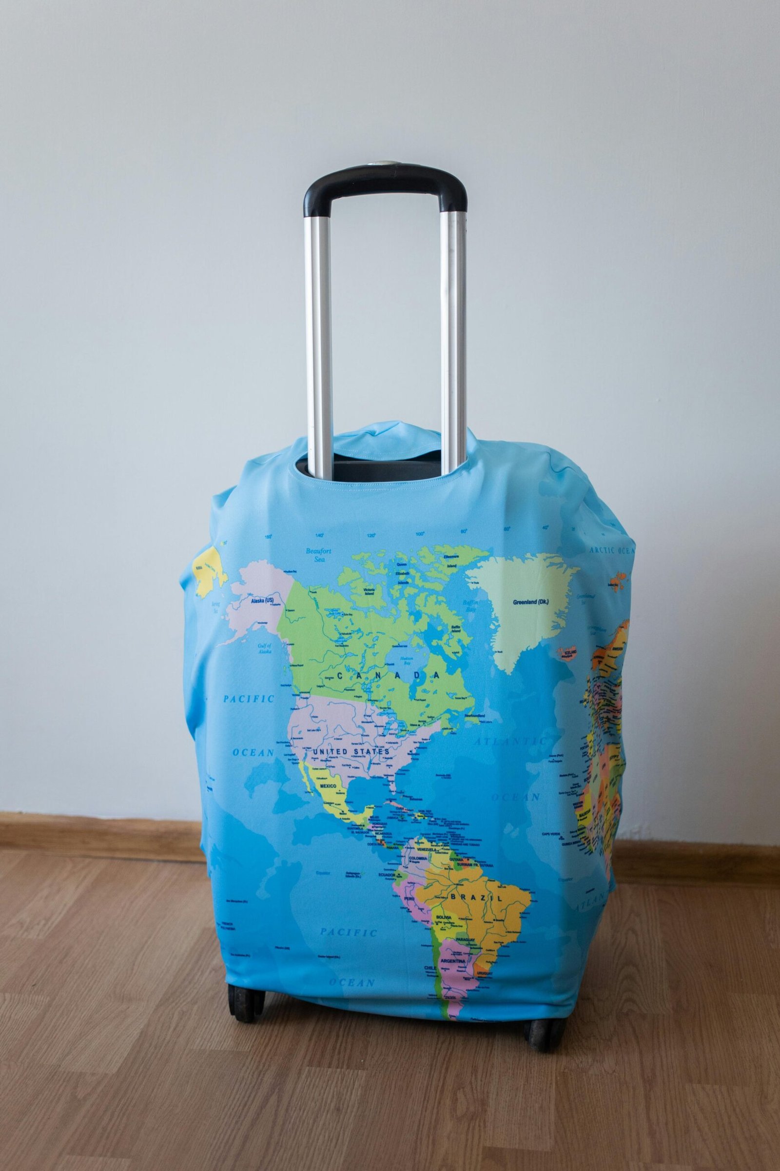 Home Blue suitcase with world map cover, perfect for travel enthusiasts. Indoor shot.